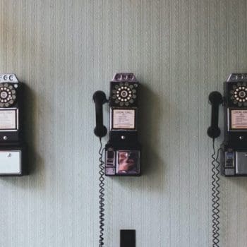 Three old dial telephones hanging from a wall