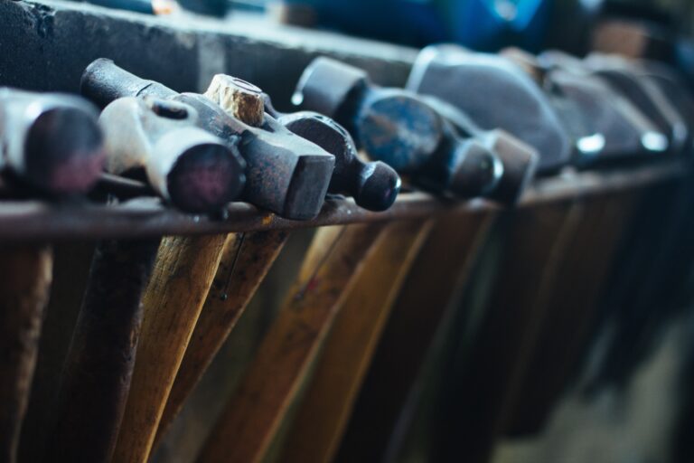 Various hammers hanging in a row from a shelf