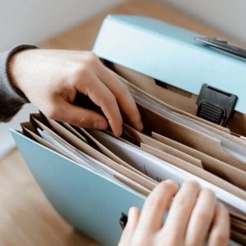 A person looking through a blue binder with various folders inside