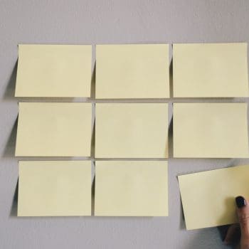 Nine yellow sticky notes placed on a wall in a square formation