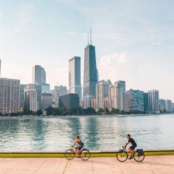 A wide shot of the Chicago skyline with bicyclists and boats visible in the foreground