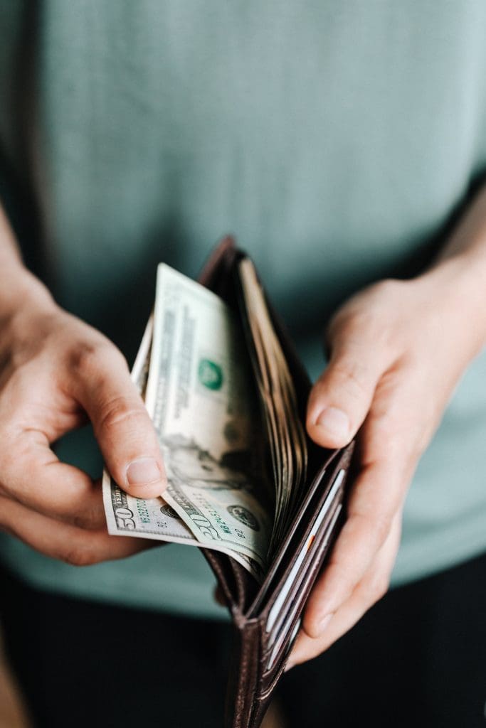 Close-up of a man pulling various bills from his wallet