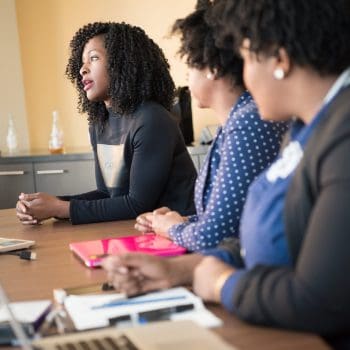 Three women sitting at a desk for a meeting