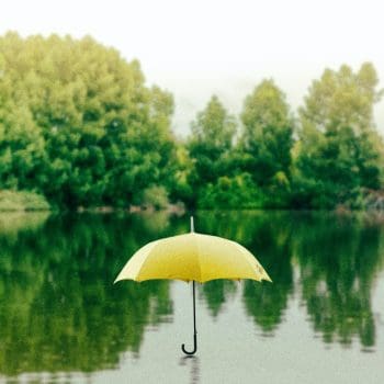 An open yellow umbrella sitting atop a body of water