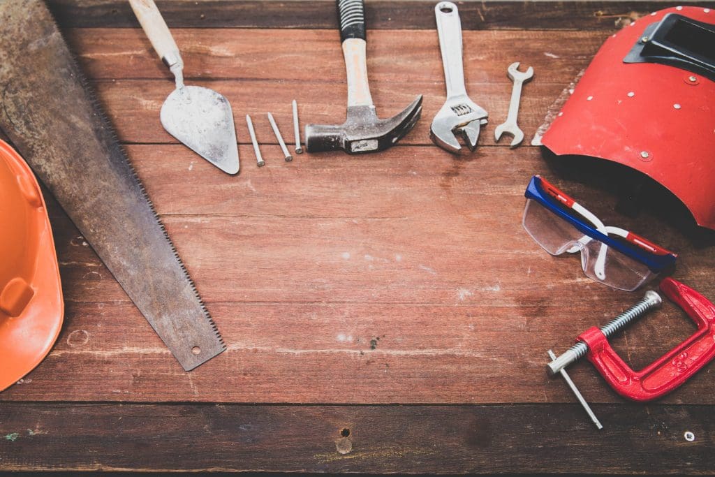 A wrench, hammer, saw, and various other tools atop a wooden table