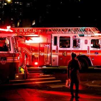 Two firetrucks stopped at an intersection at nighttime