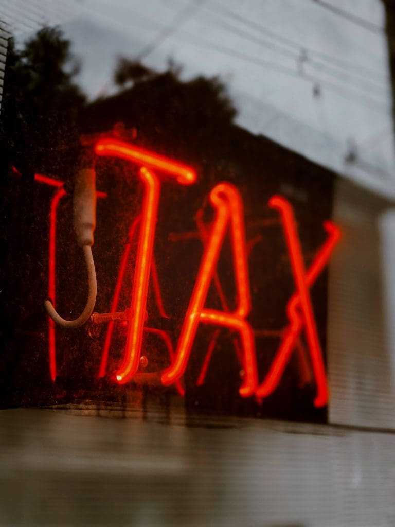 A red neon sign reading "Tax"