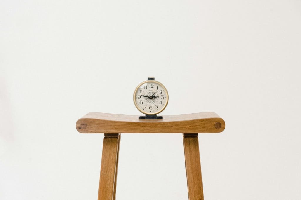 A clock sitting atop a wooden stool