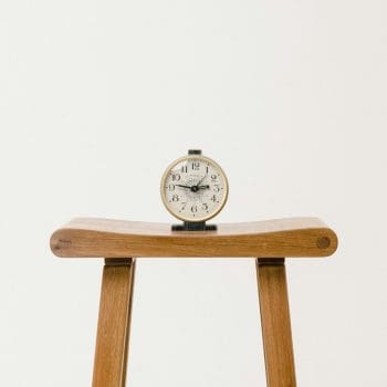 A clock sitting atop a wooden stool