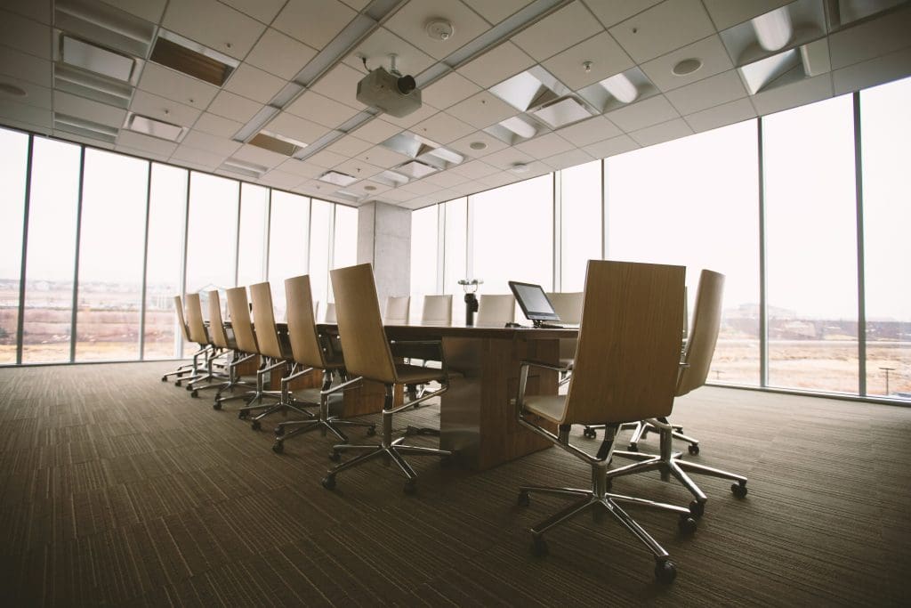 An empty workplace meeting room with chairs beside a long desk