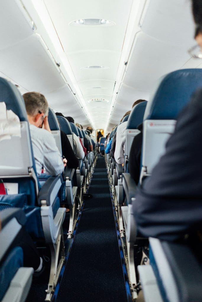 Shot from the center aisle on a plane of passengers in their seats