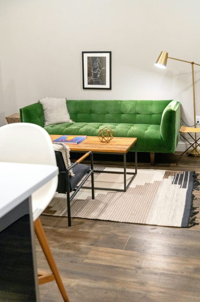 A living room with a green couch and various other decorations and furniture around it