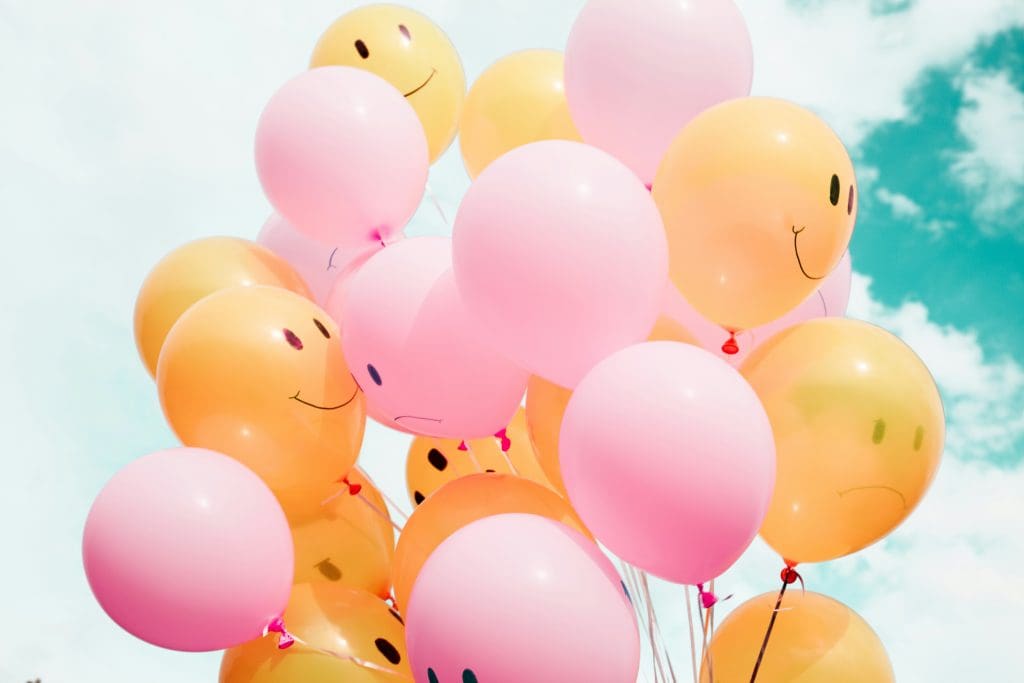 Orange and pink balloons with smiley and frowning faces